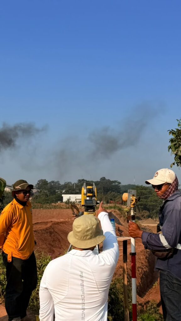 Tim surveyor melakukan pengukuran lahan menggunakan total station di area proyek konstruksi